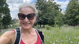 Doctor Hellen Hall standing and smiling in a green meadow with blue skies