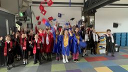 Children in graduation robes tossing their caps