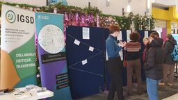 A group of people standing looking at a poster display
