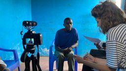 A man in Nairobi sitting in front of a camera being filmed for an interview