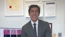 A person smiling at the camera sitting on a desk.