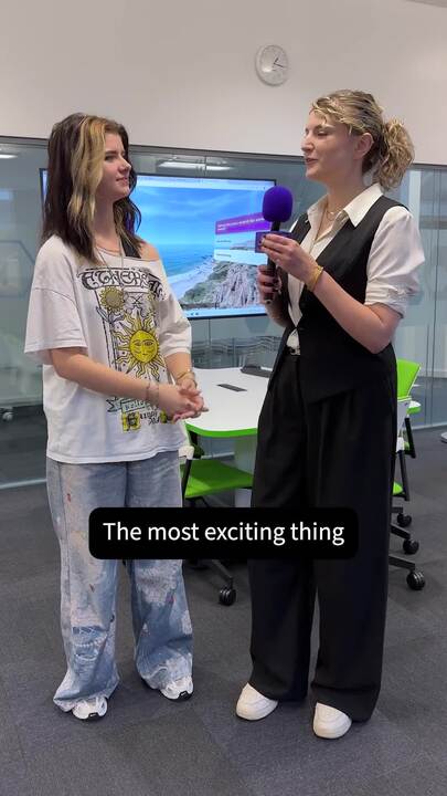 A person holding a microphone stands beside another person